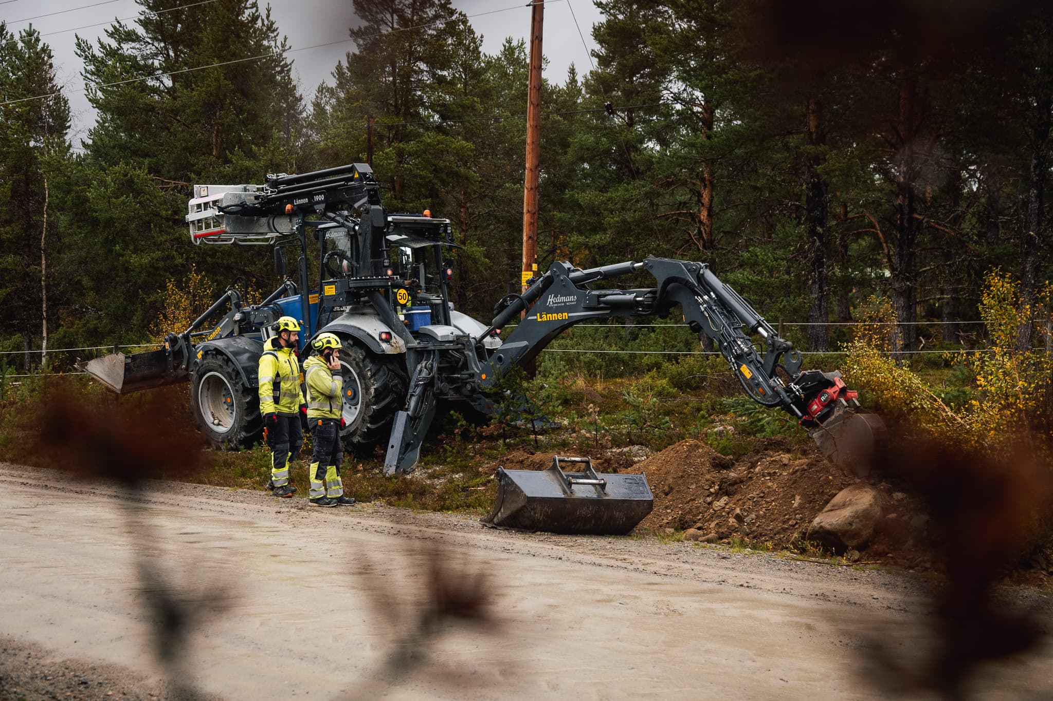 Grävlastare med skylift som arbetar vid elledningar under utbyggnad av elnät och fjärrvärme i södra Jämtland av BTEA.